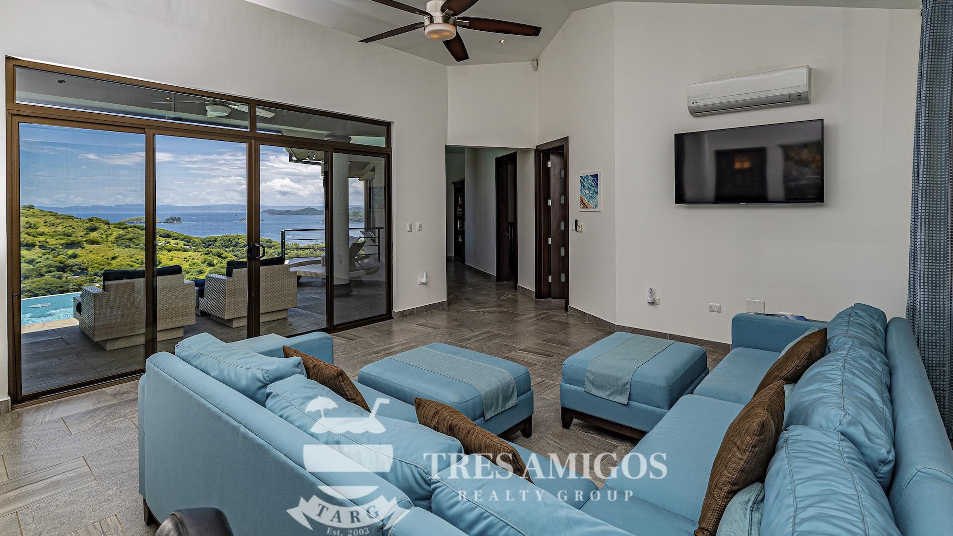 ocean view living room with ceiling fan and sliding glass door